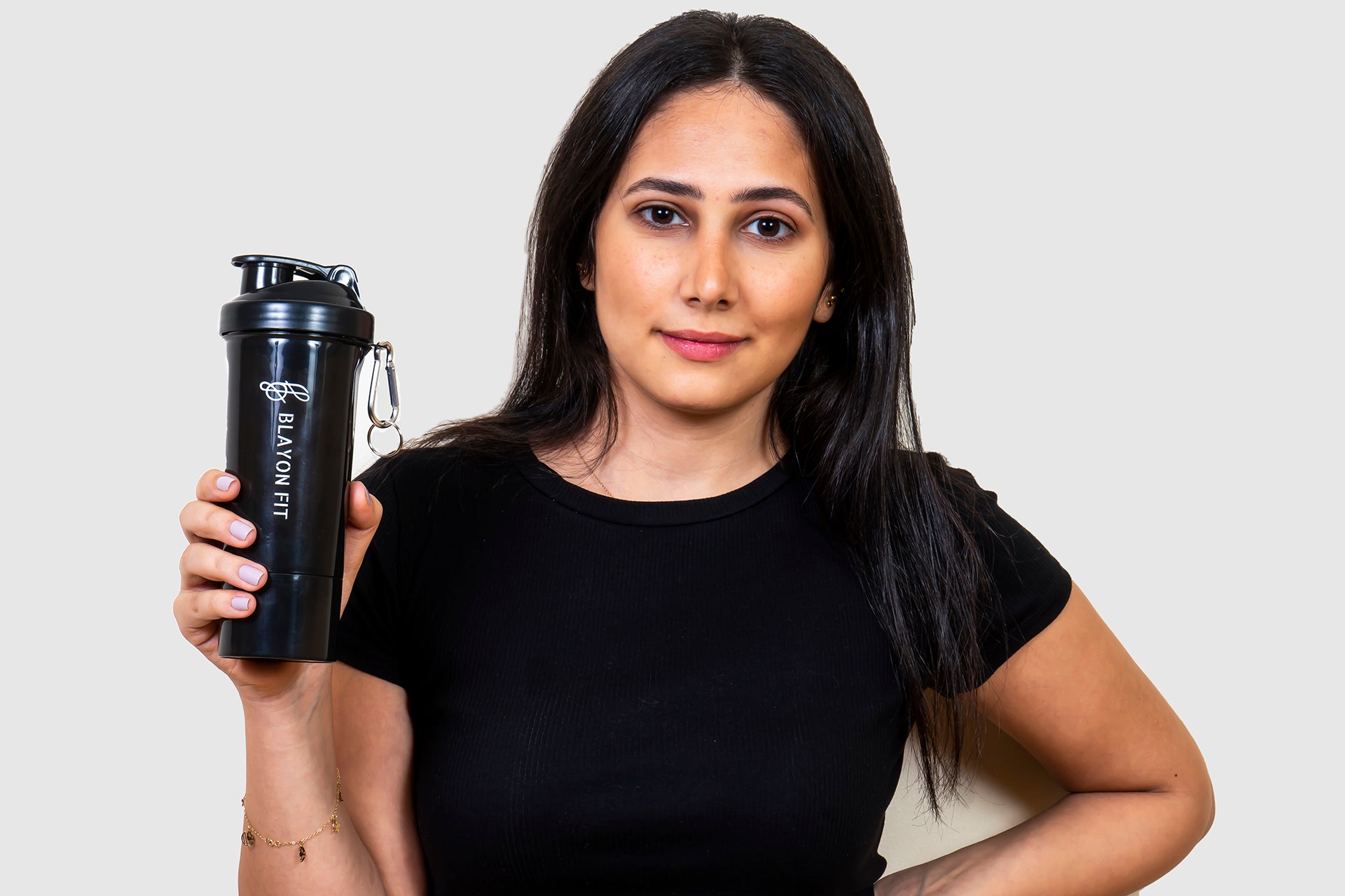 woman holding a protein shaker that is high quality and has a storage for supplements. 