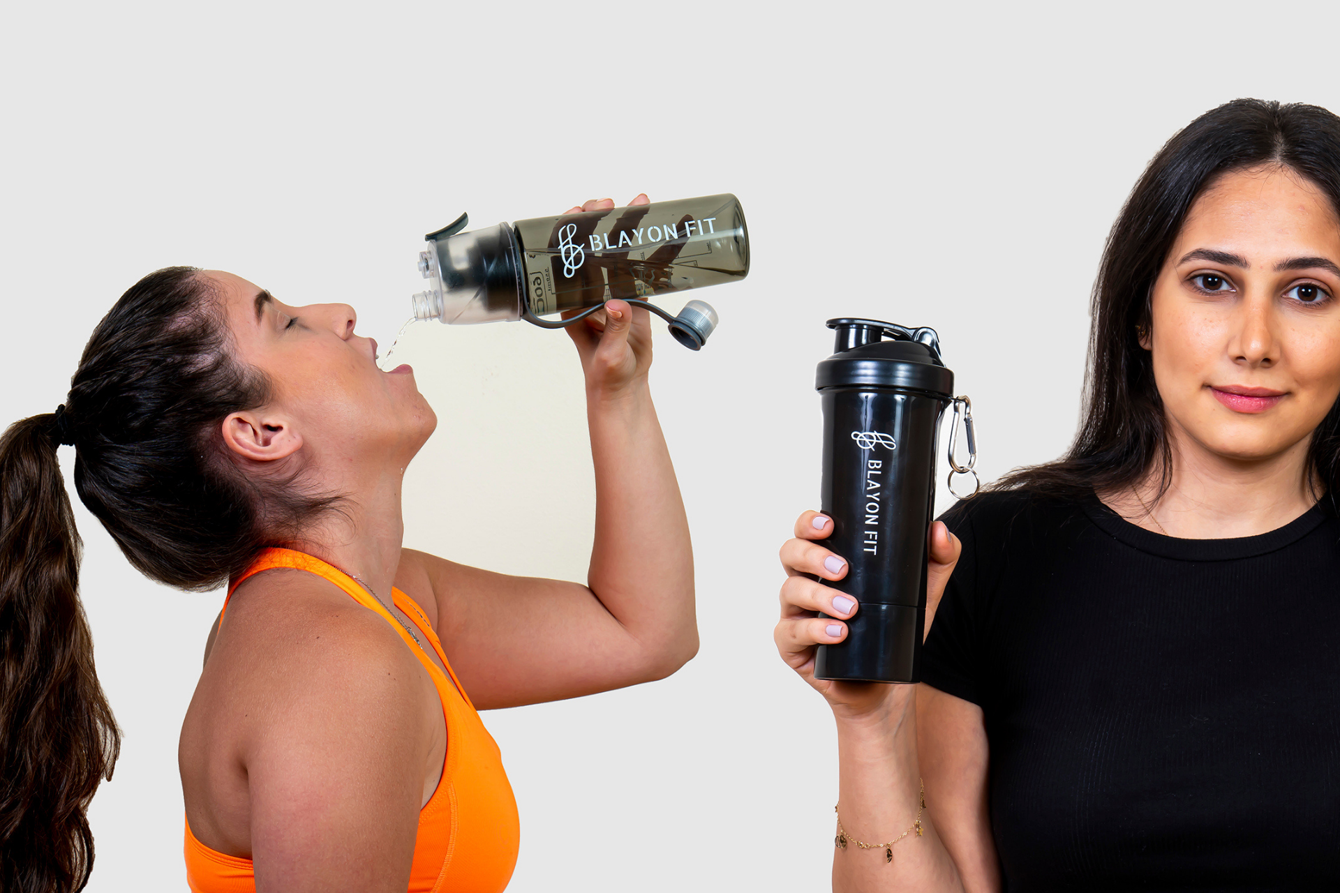 girl drinking water from a gym water bottle and another girl is holding a protein shaker.
